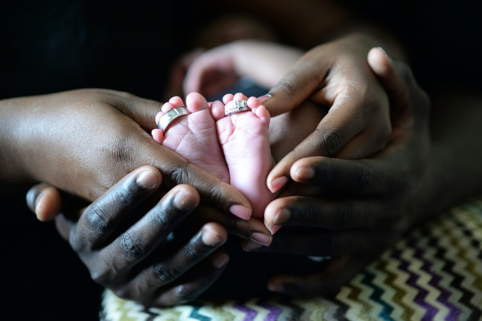 person touching baby's feet with two silver-colored rings